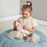 Young girl holding a rag doll on a blue cushioned chair