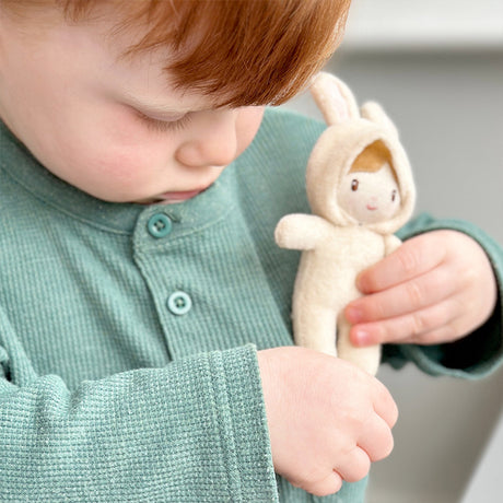 Child holding a soft toy with a neutral background