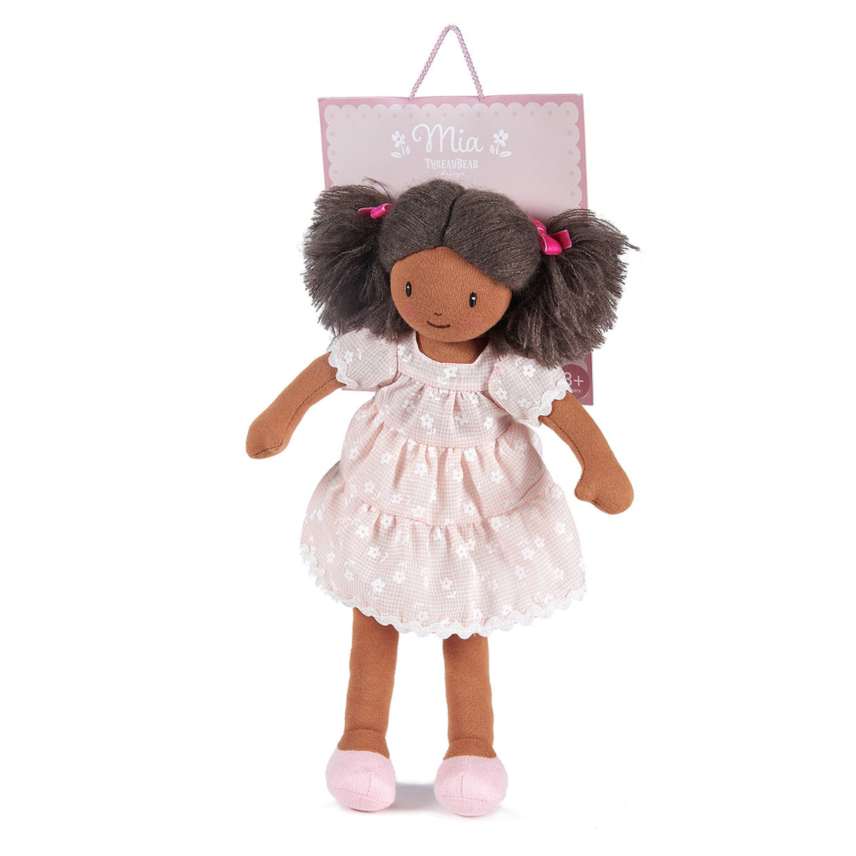 Doll with a white dress and pink shoes hanging on a pink name tag with 'Mia' on a white background