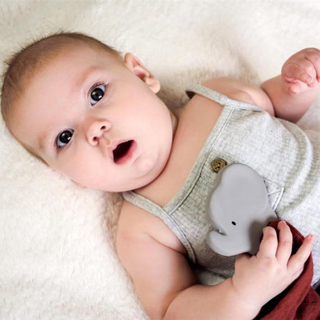Baby lying holding an organic rubber elephant teether soother blankets