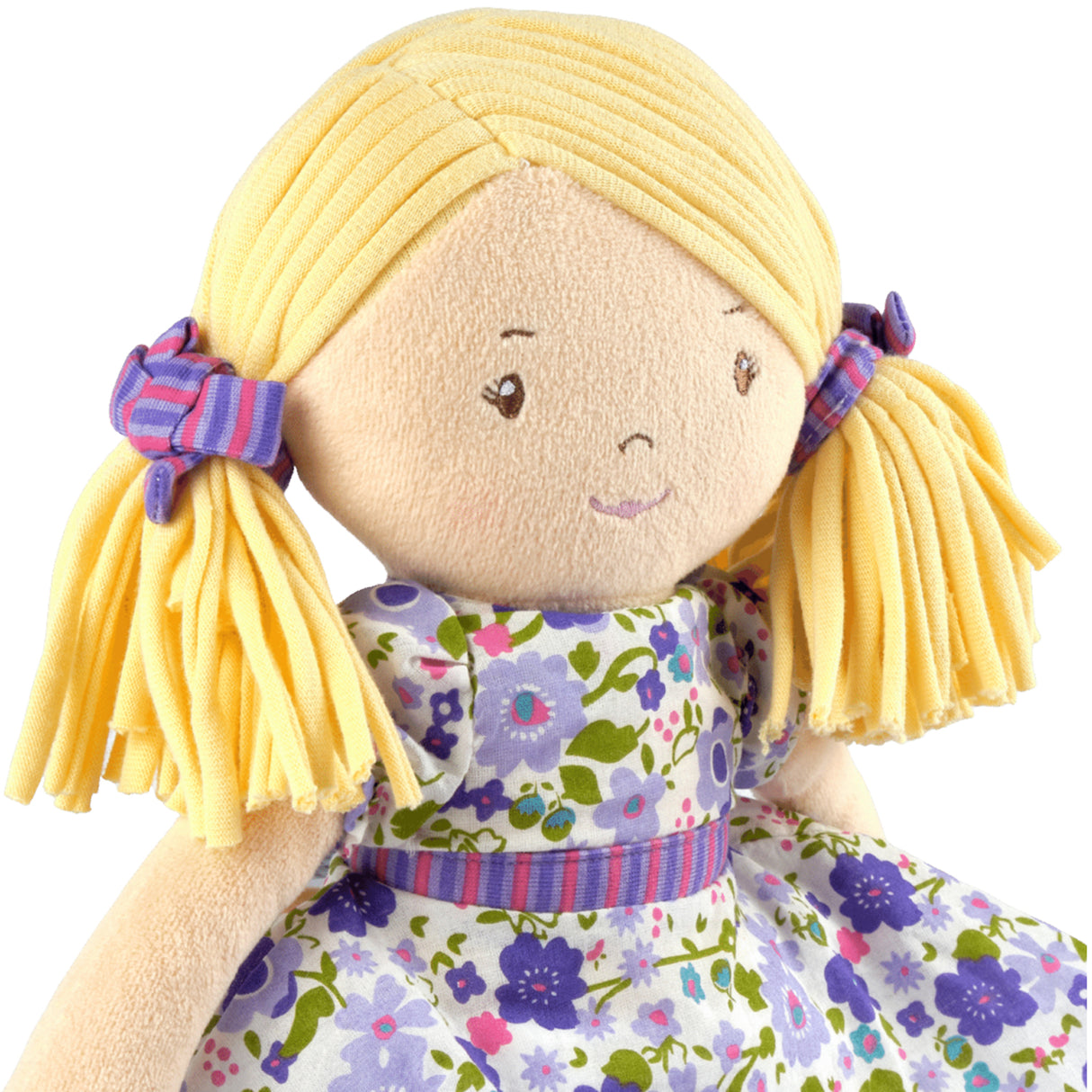 Plush rag doll with blonde hair in pigtails wearing a floral dress on a white background