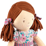 Soft rag doll with brown hair with pigtails wearing a floral pink and turquoise dress