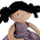 Soft doll with black hair and a colourful dress on a white background