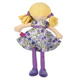 back view of soft rag doll with blonde hair, purple and green floral dress, and striped leggings on a white background 