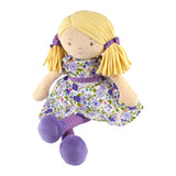 Soft rag doll with blonde hair, purple and green floral dress, and striped leggings on a white background