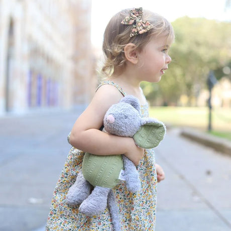 child holding an organic soft toy mouse with grey fur and green ears and tummy outside