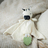 A baby muslin comforter with an attached zebra toy and green leaf teether