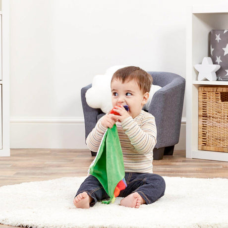Child playing with The Very Hungry caterpillar Green comfort blanket with colorful rainbow edges and  tags. 