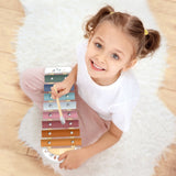 Child playing with a colourful toy xylophone on a white rug