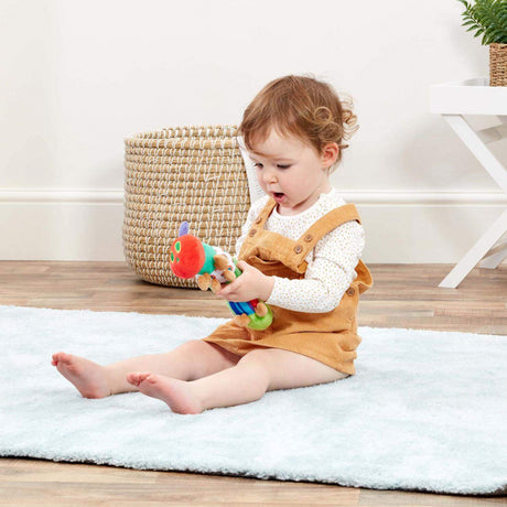 Child playing with a toy on a white rug in a room with a basket and plant.