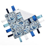 Fabric taggie blanket with blue animal pattern and colourful tags on a white background