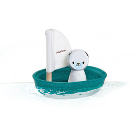 Toy boat with a polar bear and sail on a white background, branded 'Plan toys'.