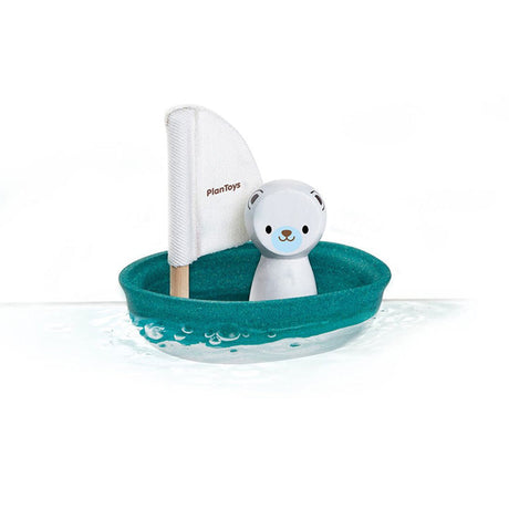 Toy boat with a polar bear and sail on a white background, branded 'Plan toys'.
