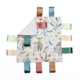 A square baby taggy comforter with a woodland animal print, featuring a white plush reverse side and colourful satin ribbon tabs in blue, green, pink, beige, and brown.