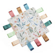 A square baby taggy comfort blanket with a  colourful woodland animal print, featuring soft satin ribbon tabs in blue, pink, green, and gold around the edges,