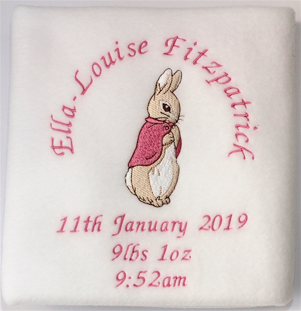 A folded beautifully handmade personalised and embroidered Beatrix Potter Flopsy Bunny Blanket with name and date around the bunny  