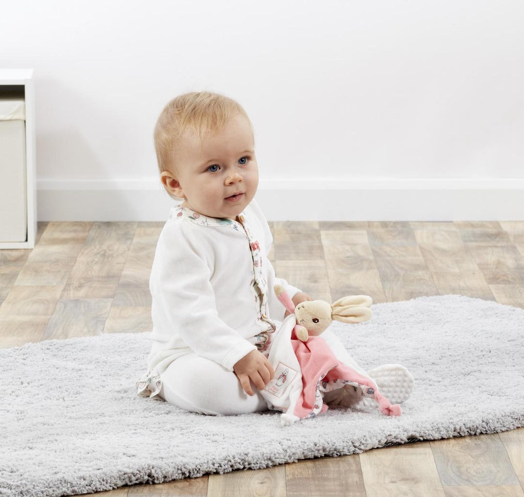 Baby holding a  white and pink Beatrix Potter Flopsy Bunny Comforter that can be personalised