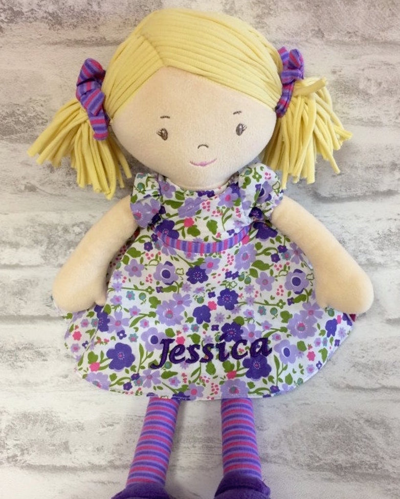 A Peggy Rag Doll from Bonikka in a purple flowery dress, blonde hair and showing personalisation 
