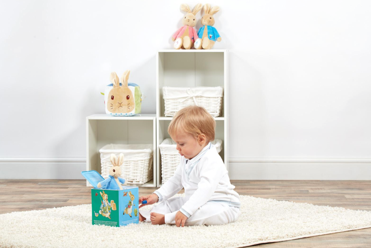 A child playing with a Beatrix Potter Peter Rabbit Jack in the Box toy gift with bunny standing up in box