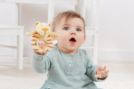 Baby holding a Hundred Acre Wood Tigger Ring Rattle for Christenings 