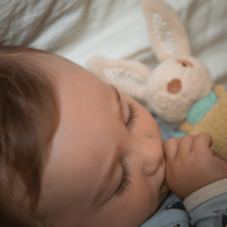 ragtales baby alfie rattle velvety brown nose with aqua knitted jumper and beige corduroy dungarees sleeping with a baby