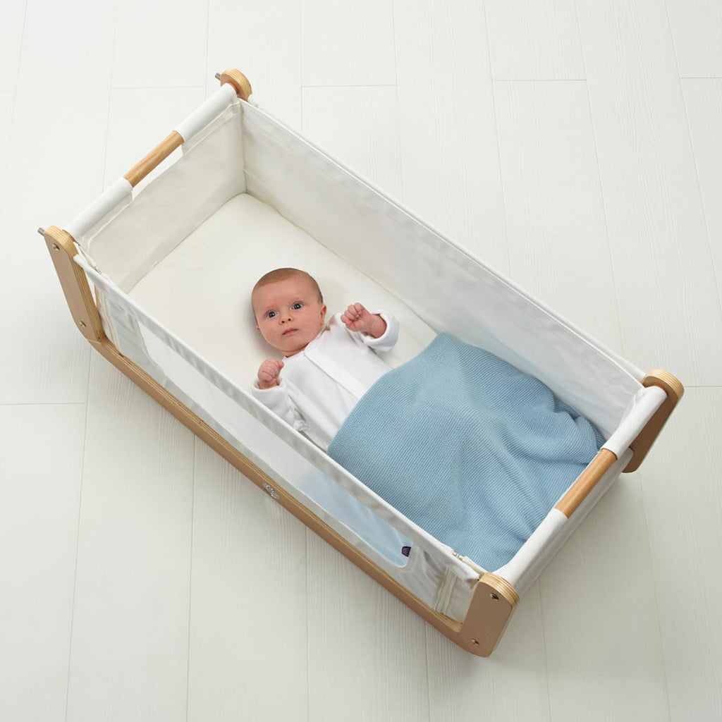 Beautiful baby in coat with a luxurious organic baby blanket of stunning quality and a simple knit design and intricate finish.