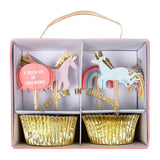 A set of gold foil cupcake cases with unicorn and rainbow toppers, presented in a box with a pink ribbon handle. The toppers include pink and white unicorns with thread tails and a 'I Believe In Unicorns' sign.